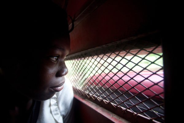A young girl stares through the grated window of a tap tap in Haiti