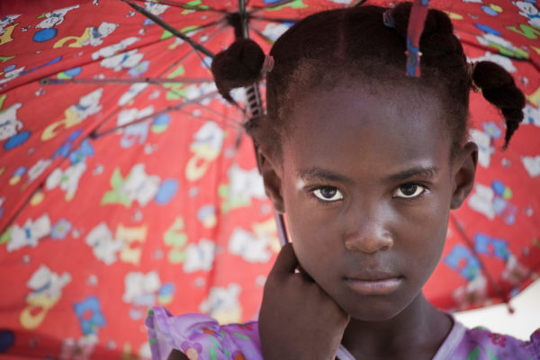 A girl shades from the heat of the midday sun on Ile de la Gonave, Haiti